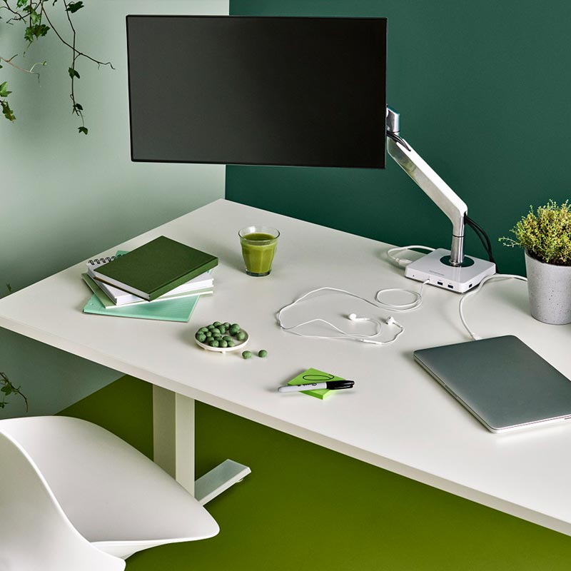 Humanscale M2 Monitor Arm on a white desk with green decor and walls